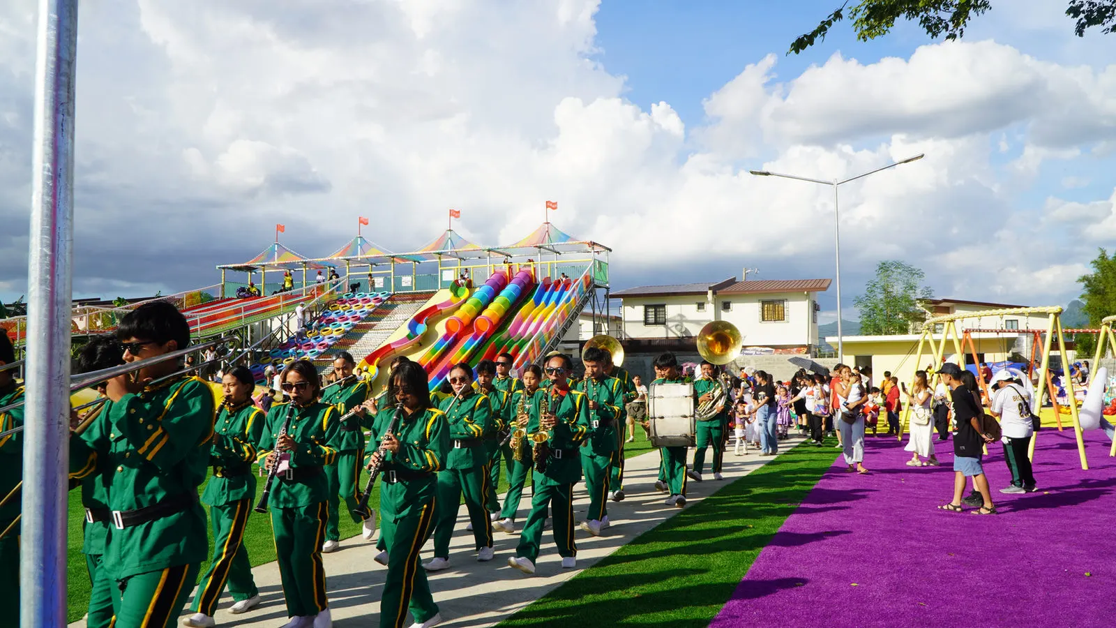 Marching band in green uniforms parading through the park
